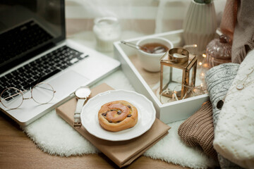 Breakfast. Laptop, mug of hot tea, bun, candle, eucalyptus in a vase. Cozy autumn. Home.