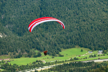 Parapendio, con paracadute rosso e tuta rossa su uno sfondo di abeti di montagna, perfetto per riviste, magazine, copertine e pubblicità
