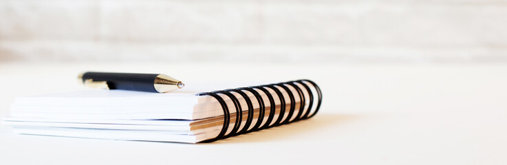 On a white background lies a notebook and a pen on it. Close-up.