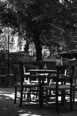 Fototapeta na wymiar table and chairs in a cafe (in the central square of a village) (black & white)