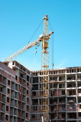 Fototapeta na wymiar tower crane at a building site during the construction of blocks of flats. Detail of residential building under construction. Concrete structure with metal struts. 