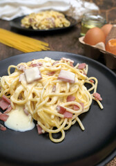 Homemade and fresh spaghetti carbonara   in a black plate on the wood table