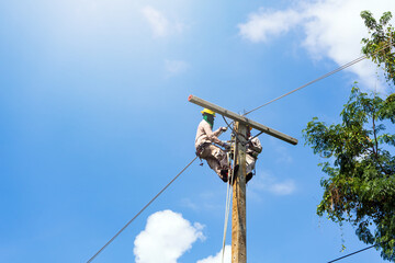 An electrician or engineer works on a power post and a high voltage system for maintenance.