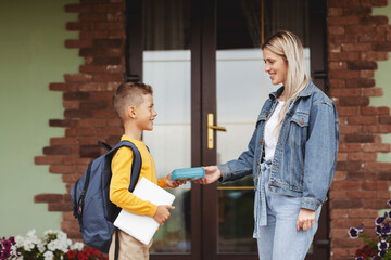 Mom escorts her son to school, serving him lunch in a box. Back to school
