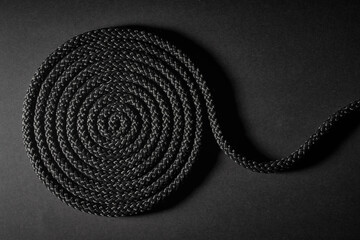 Twisted black rope in a spiral on a dark background.