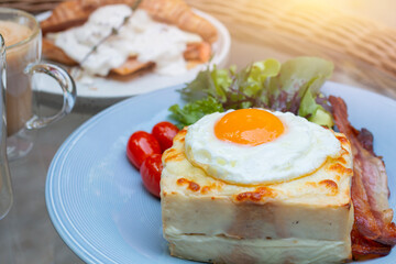 Ham and cheese sandwich with bechamel sauce and topped with a fried egg, known as Croque-madame. Croque madame sandwich on the table. Hot french toasts with ham, melted emmental cheese and fried egg.