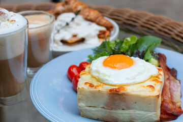 Ham and cheese sandwich with bechamel sauce and topped with a fried egg, known as Croque-madame. Croque madame sandwich on the table. Hot french toasts with ham, melted emmental cheese and fried egg.