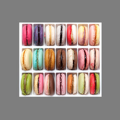 Set of 21 multi-colored macarons or macaroons with varied flavors on a gray background. Top view, copy space.