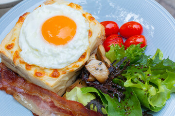 Ham and cheese sandwich with bechamel sauce and topped with a fried egg, known as Croque-madame. Croque madame sandwich on the table. Hot french toasts with ham, melted emmental cheese and fried egg.