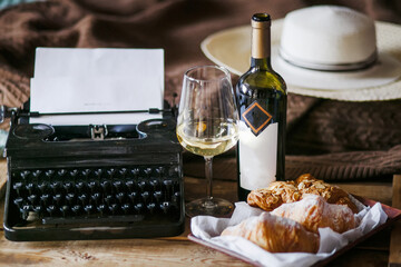 The inspiration of a writer typing texts on a vintage typewriter. Freelancer Breakfast croissants and wine. Office in the loft style