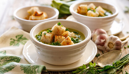 Soup Cream of zucchini and herbs with garlic croutons close up view