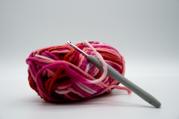 A brightly colored ball of wool with warm colors and a crochet hook