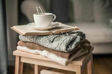 Toned photo. Autumn decor. A mug of hot tea, Knitted sweaters, book, glasses . Cozy. Autumn.