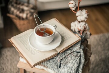 Toned photo. Autumn decor. A mug of hot tea, Knitted sweaters, book, glasses . Cozy. Autumn.
