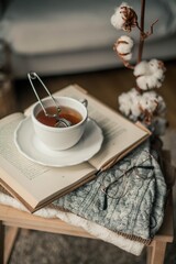 Toned photo. Autumn decor. A mug of hot tea, Knitted sweaters, book, glasses . Cozy. Autumn.