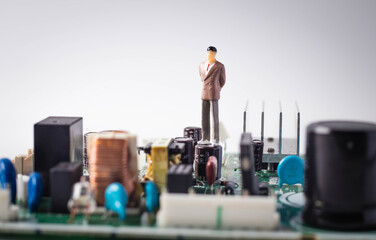 Miniature people, businessmen standing on the electronic circuit board. Business concept