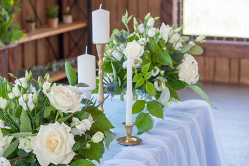Flower arrangements with white flowers stand on a table with a blue tablecloth