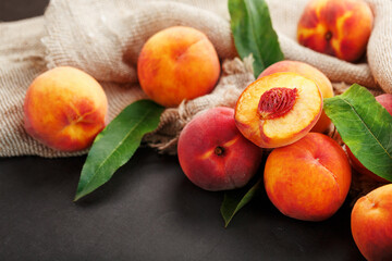 Sweet Peaches on a sharp stone table with a cloth of burlap and a slice of juicy peach with a bone.