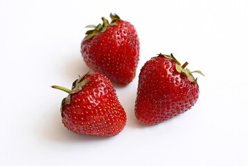 Three ripe strawberries lie on a white background