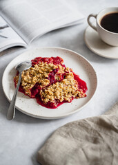 Plum crumble on white plate with coffee