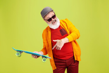 Moving skate. Portrait of senior hipster man in fashionable eyewear isolated on green studio...