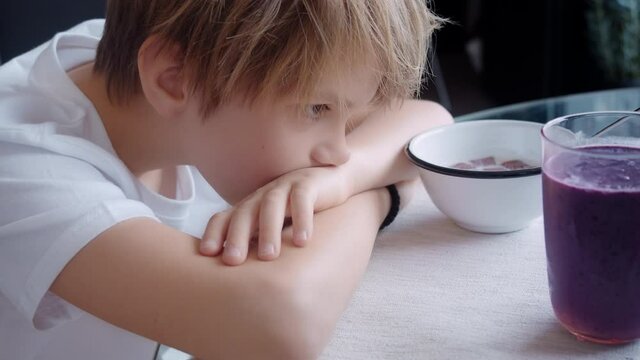 Portrait of the cute little boy looking to his healthy breakfat at the kitchen table