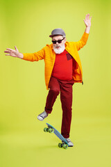 Moving skate. Portrait of senior hipster man in fashionable eyewear isolated on green studio...