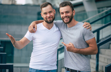 Two happy excited handsome bearded best friends in casual clothes are handshaking, hugging while...