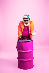 DJ. Portrait of senior hipster man in fashionable eyewear isolated on pink studio background. Tech...