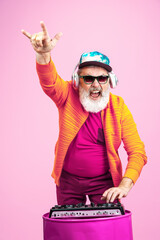 Party drive. Portrait of senior hipster man in fashionable eyewear isolated on pink studio background. Tech and joyful elderly lifestyle concept. Trendy colors, forever youth. Copyspace for your ad. - obrazy, fototapety, plakaty