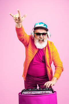 Party drive. Portrait of senior hipster man in fashionable eyewear isolated on pink studio background. Tech and joyful elderly lifestyle concept. Trendy colors, forever youth. Copyspace for your ad.