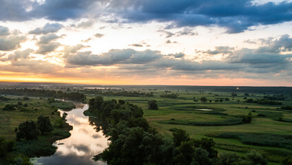 Panoramic view of river between fields during sundown.