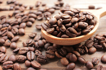 Freshly roasted coffee beans in wooden spoon on wood background. Rustic style