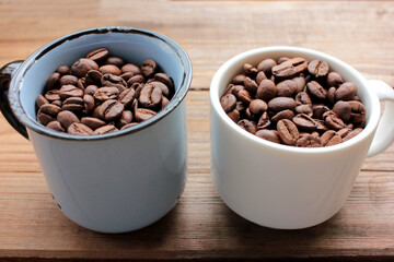 Cup of coffee beans on a wooden table. Close-up of coffee beans in ceramic cups on wood background with copy space. Rustic style
