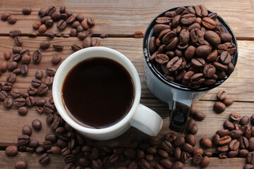 Cup of coffee with beans. Black coffee and scattered coffee beans on wooden table from above. Flat lay food composition