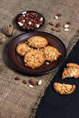 Homemade peanut cookies on a brown plate with raw peanuts in background
