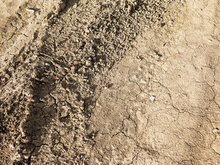 Traces of off-road tires. Cracked earth on country road with traces of tires, cars, cracks and dirt. To use as background.