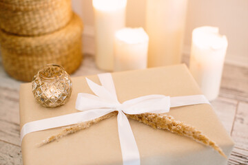 Box with New Year's gift on background of burning candles. Selective focus.