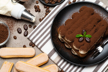 Classic tiramisu dessert and savoiardi cookies on ceramic plate on concrete background