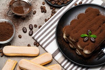 Classic tiramisu dessert and savoiardi cookies on ceramic plate on concrete background