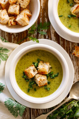 Creamy soup of zucchini and herbs with garlic croutons top view. Healthy vegetarian food