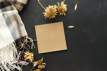 Autumn background top view. Greeting cards mockup template, invitations blank, cup of coffee, scarf, dried flowers on black paint textured  background. Flat lay, copy space. Autumn, fall concept.   