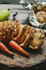 Baked chicken breast. Wooden background. Chicken breast, baked carrots, knife, on a wooden board. Closeup. Vertical view