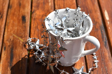 Silver Christmas, cup and stars on wooden background.