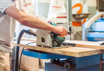 Man works with a circular saw in a carpentry workshop