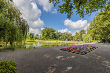 Esplanade in front of the fishing pond with planters with pink, purple, yellow and white flowers...