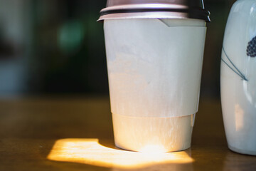 Paper cup of coffee on table with high contrast lighting.