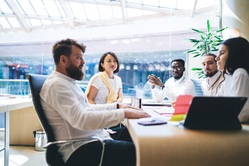 Multiracial group dressed in smart casual wear discussing financial analytic during brainstorming process, diverse male and female employees analyzing information communicate about marketing plan