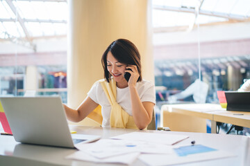 Asian woman chatting on cellphone in office