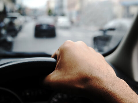 Blurred photo of hand holding the car steering wheel ,
man driving a car
